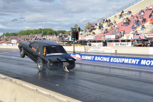 fox body mustang doing a wheelstand at dragstrip