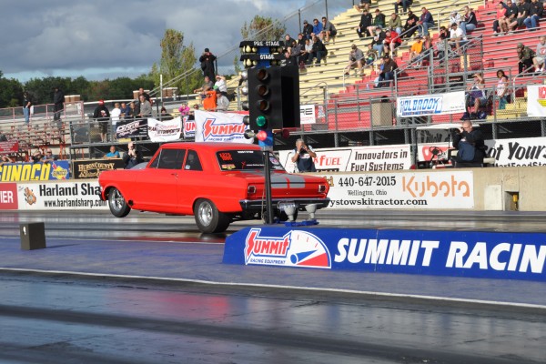 chevy 2 nova drag car doing a wheelstand at drag strip