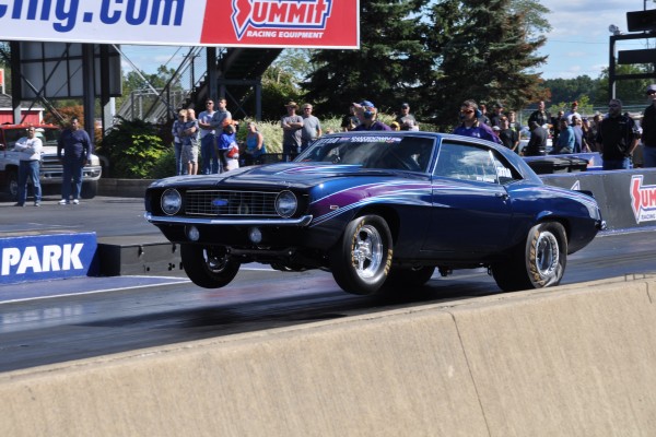 1968 chevy nova drag car doing a wheelstand at dragstrip