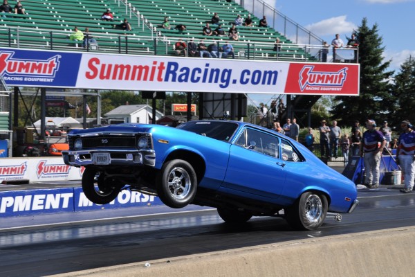 vintage chevy nova drag car doing a burnout at dragstrip