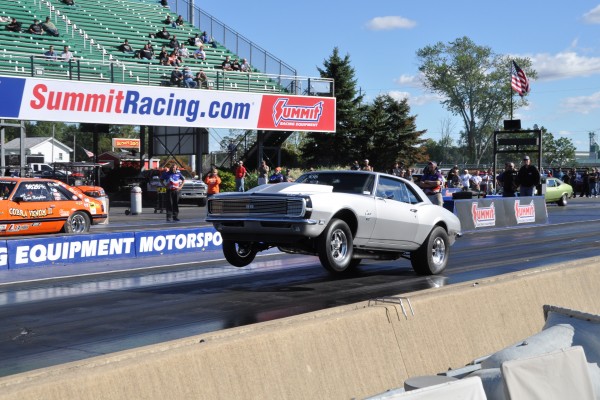 a silver 1968 chevy camaro launching at a dragstrip