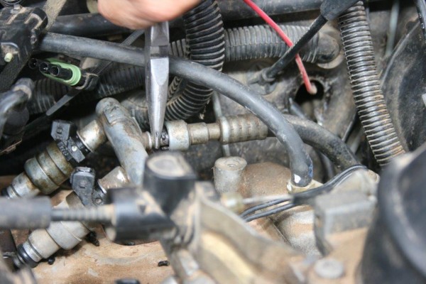 man removing a fuel line on a jeep amc 4.0L engine