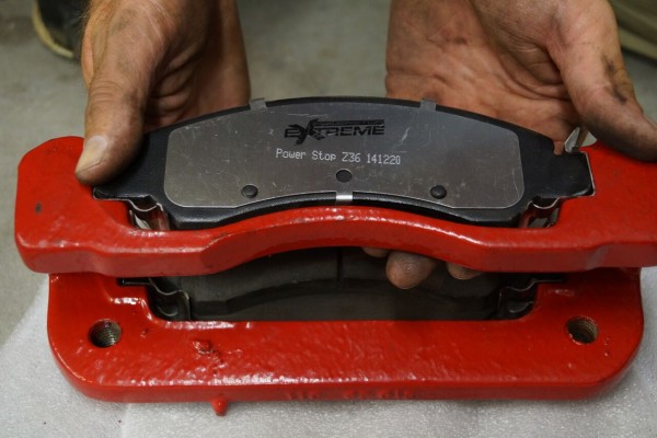 man holding a disc brake pad near caliper