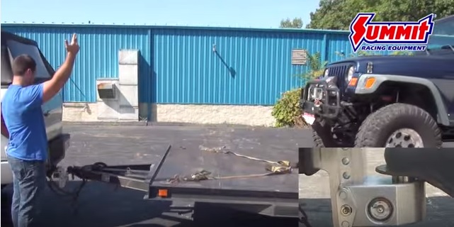 man bringing jeep onto a vehicle trailer