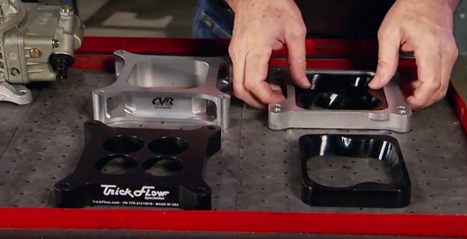 a quartet of carburetor spacers on a workbench
