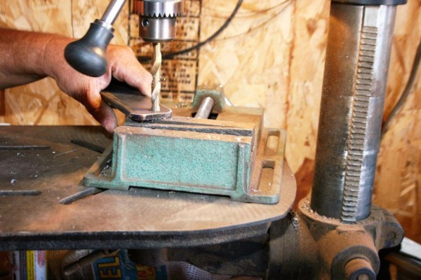 man drilling a piece of metal bar stock on a press