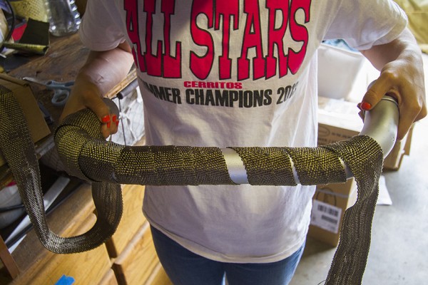 woman holding an exhaust pip partially covered in exhaust wrap