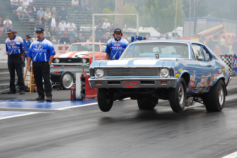 a chevy nova muscle car launching at a drag strip