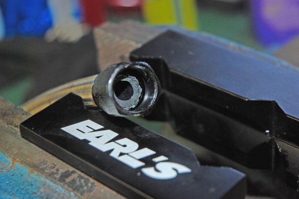 a braided hose fitting in a bench vise