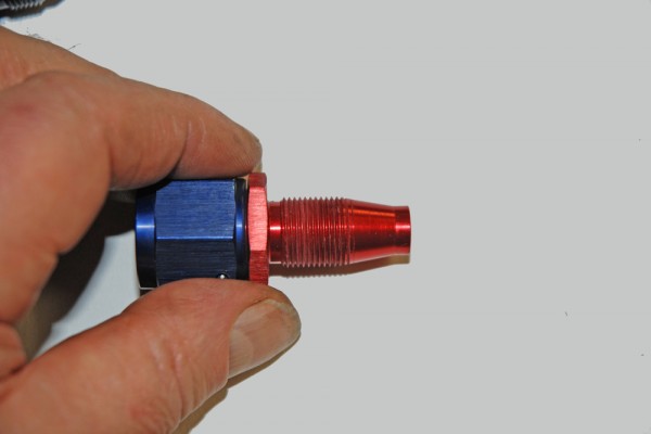 man holding an AN fitting for a fuel hose