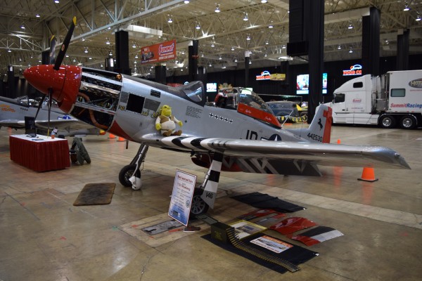military aircraft on display at indoor car show