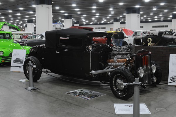 black ford hotrod with dual quad intake at indoor car show