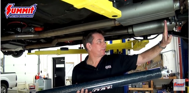 man underneath muscle car on lift