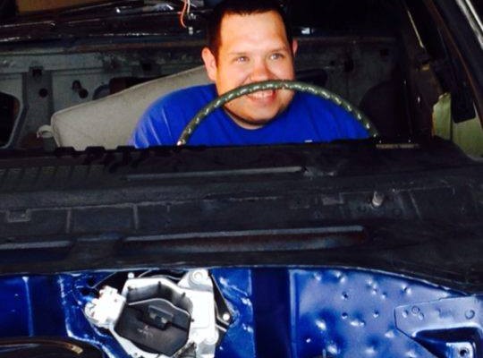 man sitting behind steering wheel of car in restoration