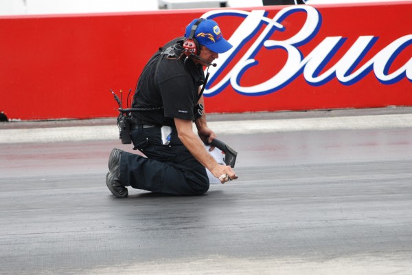 man checking track temperature at drag strip
