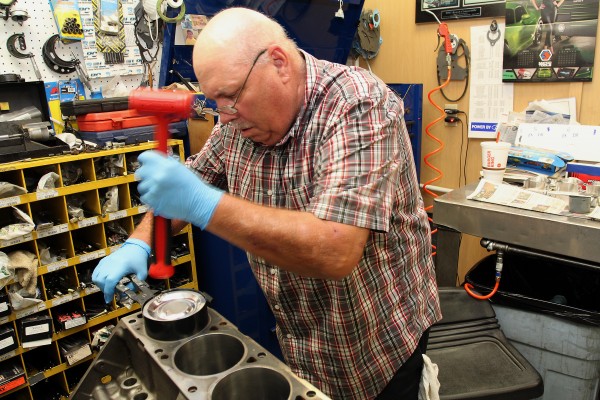 man fitting pistons into an engine
