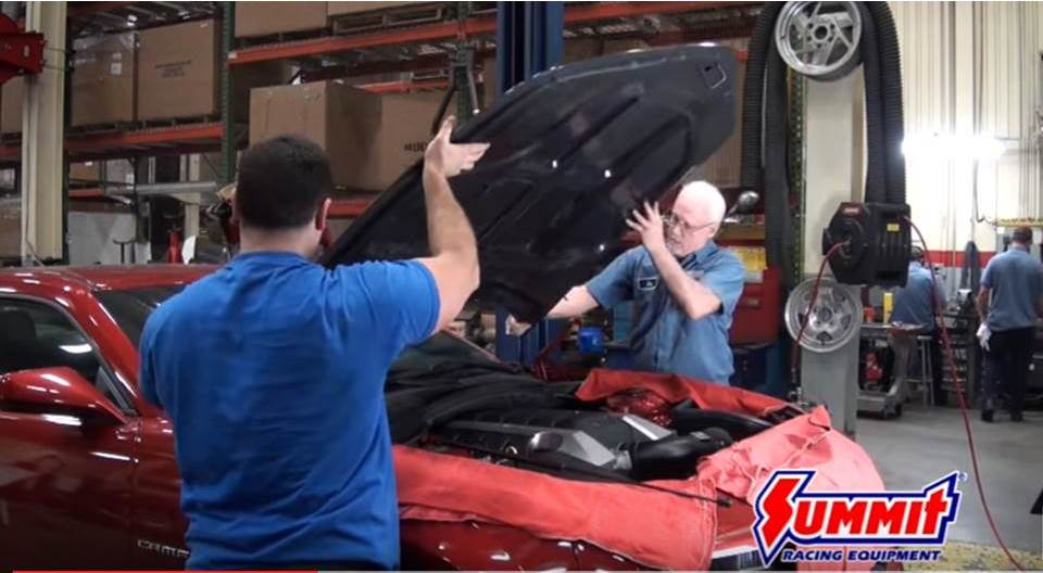 men fitting hood onto late model camaro car