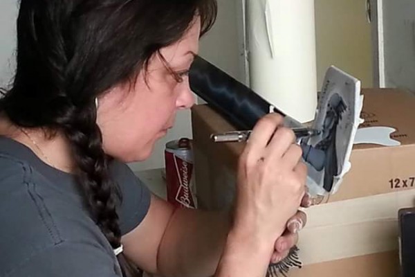woman airbrushing custom paint on an AMC AMX