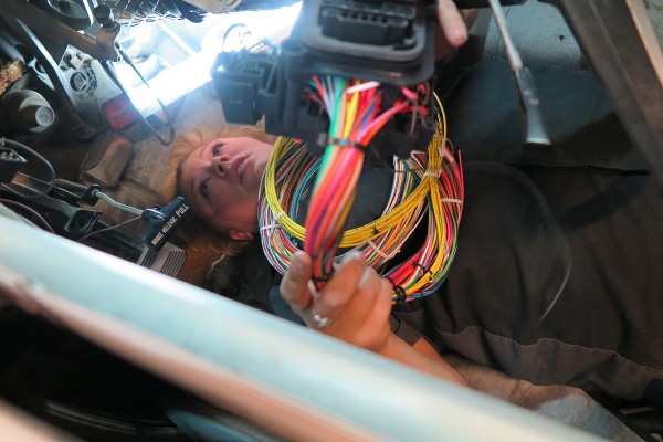 woman running vehicle wiring harness through an AMC AMX