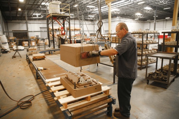 man putting top on sand casting mold in factory