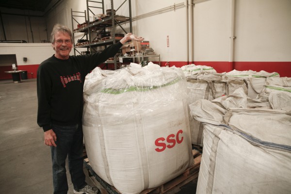 man grabbing handful of sand out of a big bag
