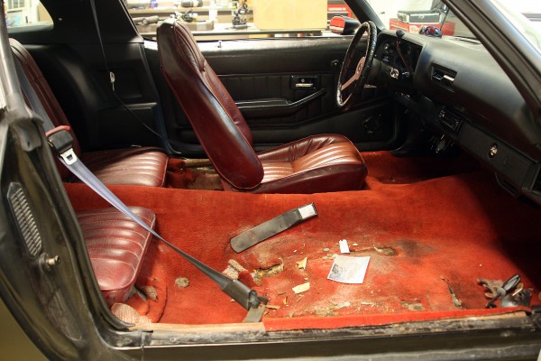old red interior of a vintage chevy camaro with seat removed