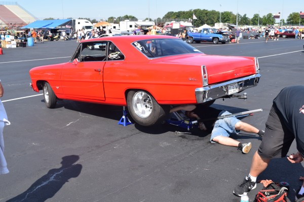 man working on vintage chevy 2 nova drag car in parking lot