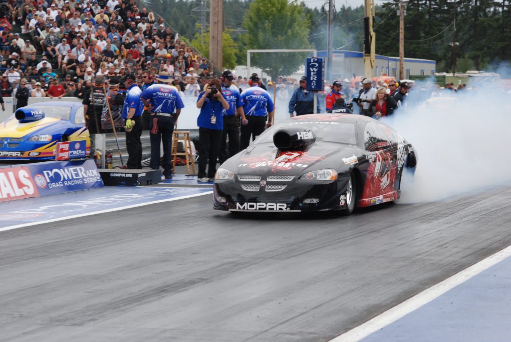 dodge avenger pro stock car doing a burnout at a dragstrip