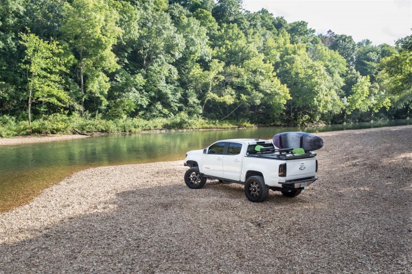 truck with paddle board rack parked near a stream