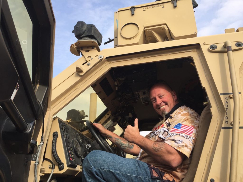 man posing in cabin of military vehicle