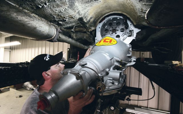 man installing tci transmission in a car