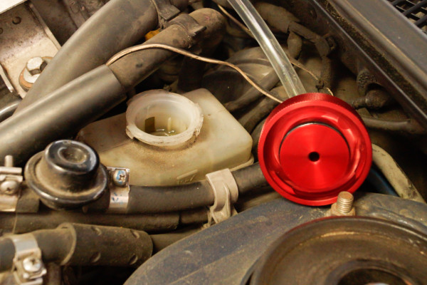 a pressurized cap getting installed on a brake master cylinder reservoir