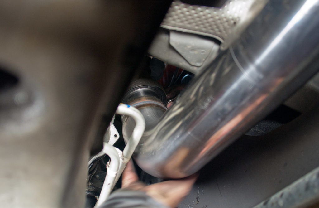 man fitting exhaust section into vehicle