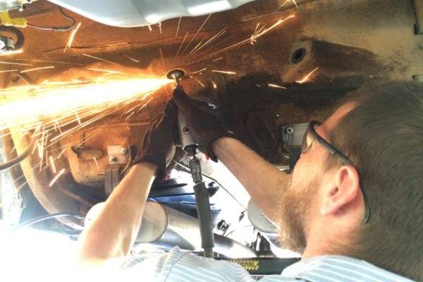 man cutting under body of 1968 ford mustang