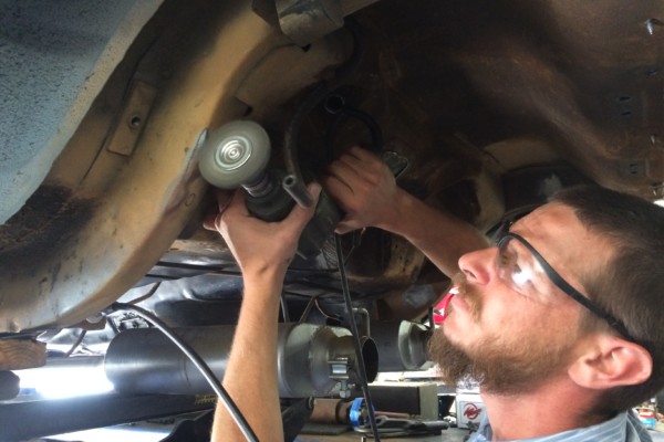 man grinding frame rail in 1968 ford mustang