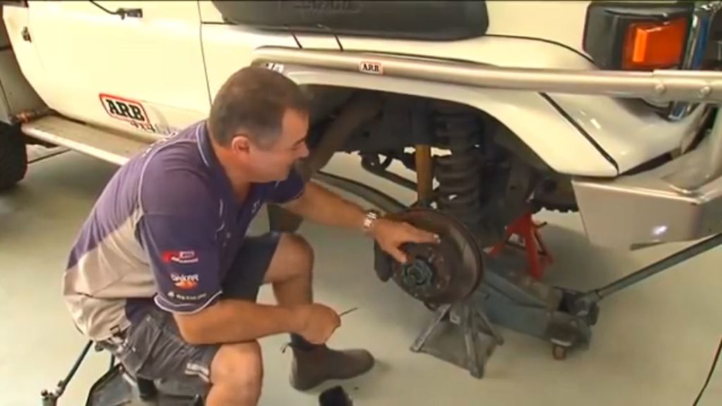 man inspecting brake disc on off road truck