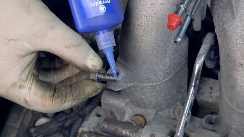 Threadlocker being applied to an engine bolt thread