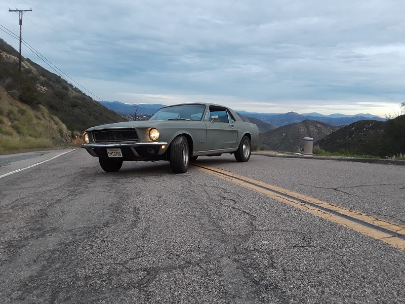 first gen mustang notchback coupe parked sideways on a road