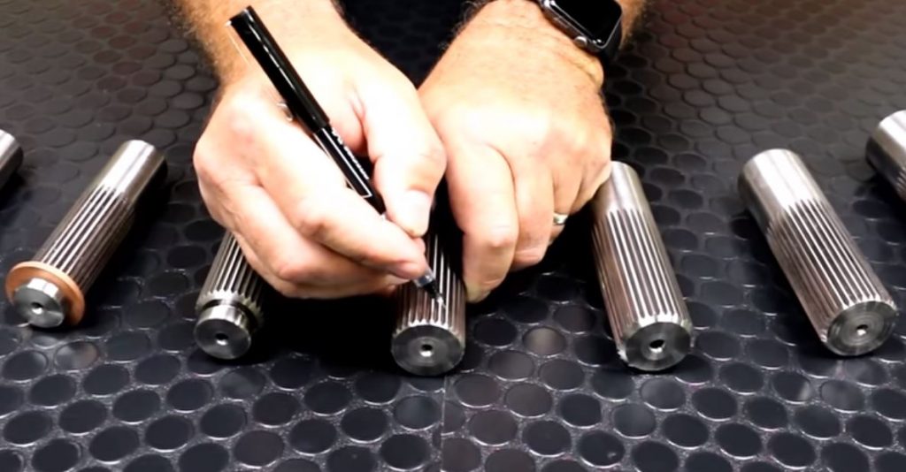man marking splines on an axle shaft with a marker