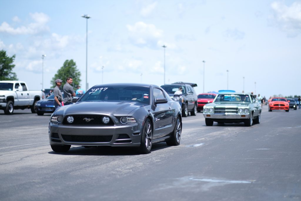 row of cars leaving a classic car show