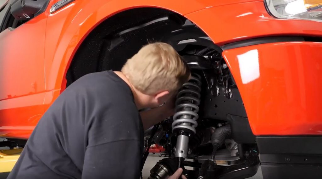 Man installing fox off road shocks on a ford f-150 truck