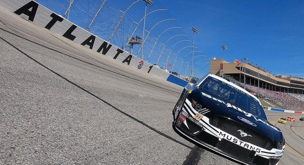 a ford mustang stock car drives on a curve at Atlanta motor speedway