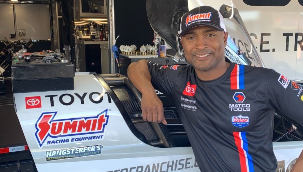 antron brown poses in the pits alongside his nhra top fuel dragster