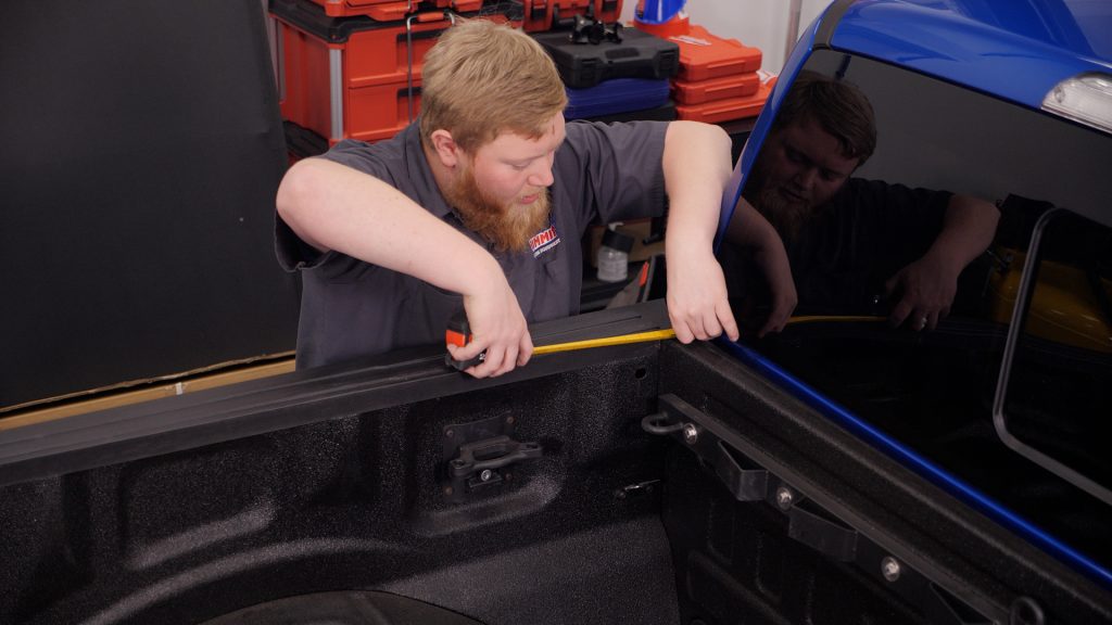 man measuring a truck bed length at the bulkhead