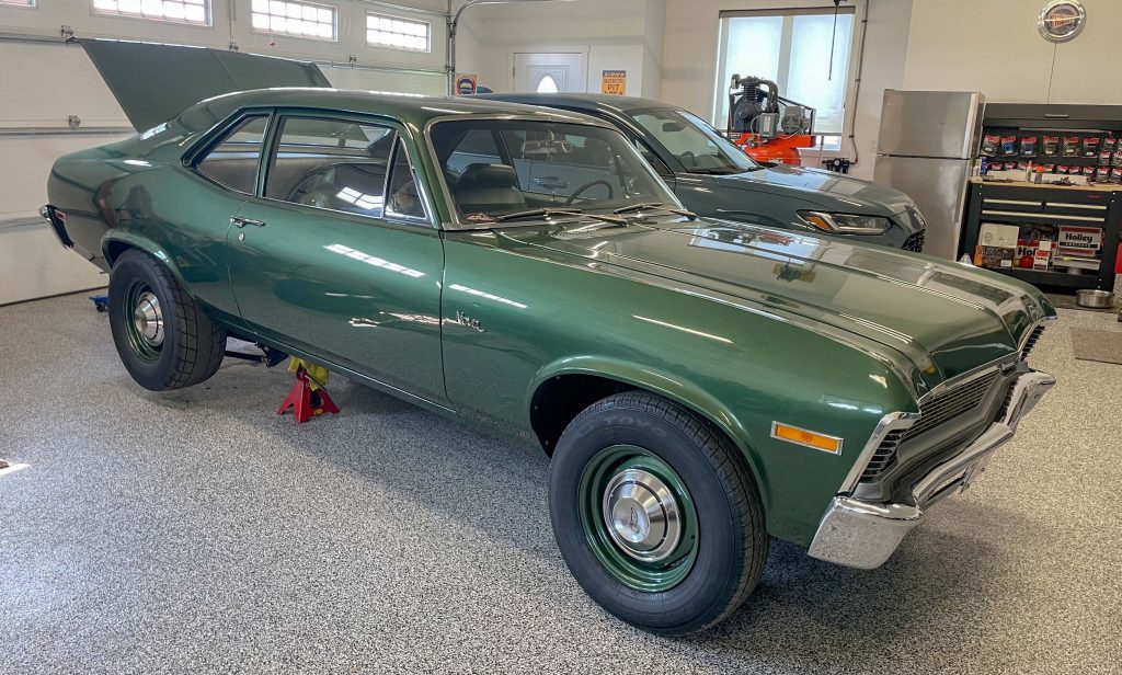 chevy nova muscle car with rear end raised on jack stands in garage