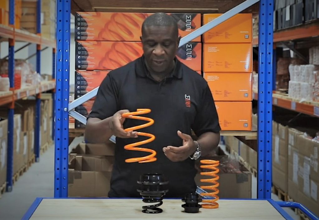 Man demonstrating how an automotive coil spring settles