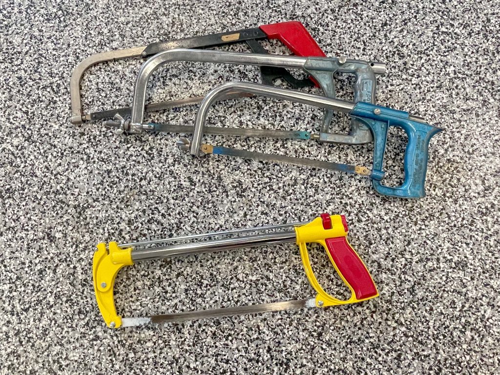 Multiple hacksaws laid out on a garage floor