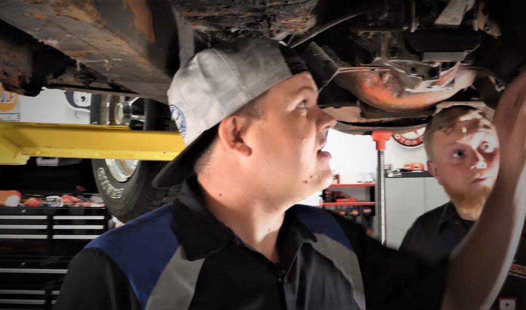 Robby Layton inspecting a vintage car chassis on a lift