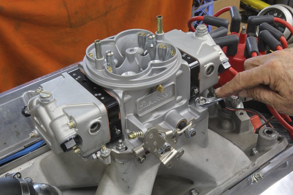 Edelbrock VRS-4150 carburetor getting bolted to engine