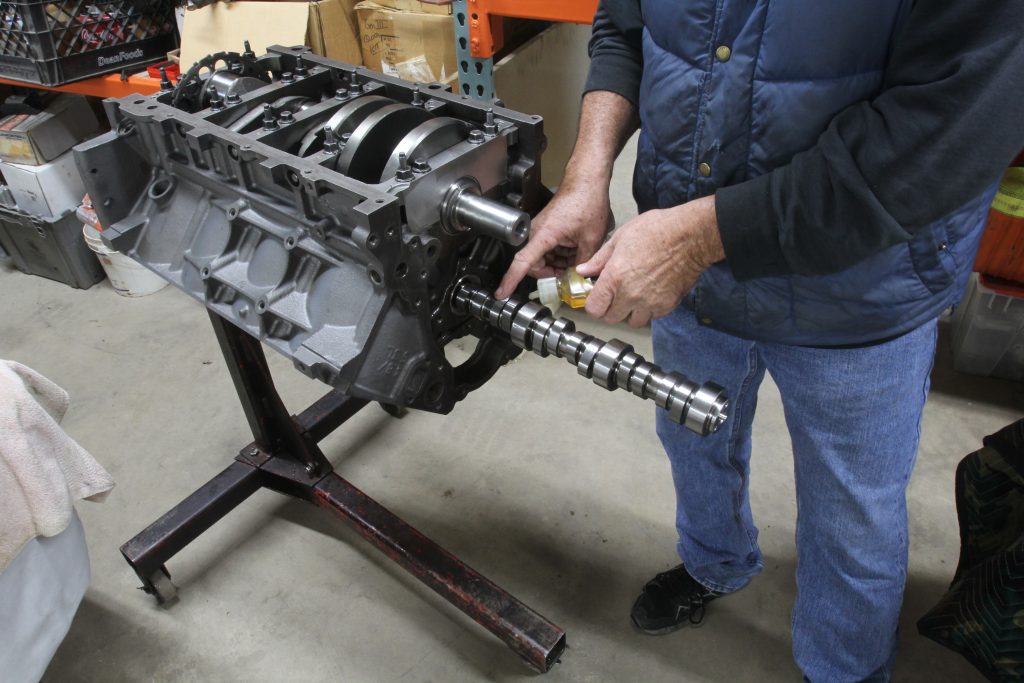 man lubing a camshaft during installation